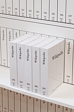 Plusieurs livres blancs à la typographie sobre, rangés verticalement, dont les tranches et la couverture de l'un d'entre eux sont lisibles