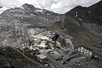 Vy över passet från Piz da las Trais Linguas. Bortom bebyggelsen vid själva passet ses pelarna till kabinbanan som leder upp till skidhotellen på över 3 000 meters höjd.