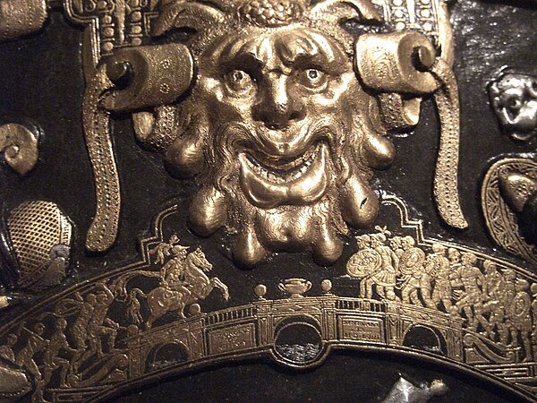 Detail from the Ghisi Shield in the Waddesdon Bequest; a grotesque head in the larger scale above Horatius at the bridge in the smaller