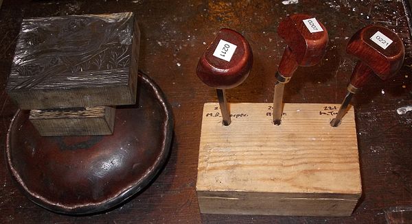 Leather-covered sandbag, wood blocks and tools (burins), used in wood engraving