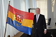 Bernd Busemann in seinem Büro im Niedersächsischen Landtag mit der Flagge des Landkreises Emsland