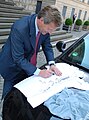 Premier of Lower Saxony Christian Wulff, patron of the white Free-Travel-Shirt signing it...