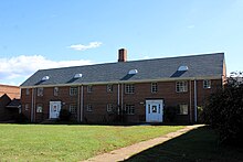 A daytime exterior photo of two Colonial Revival apartment buildings that share a common roof