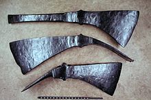 The unhafted iron heads of three early Roman tools. Top, an axe with a straight spike ending in a vertical chisel-like point, and bottom, two cutter mattocks HedemuePionieraexte1.jpg