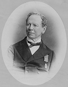 Head and shoulders image of a fair-skinned middle-aged man, wearing mid-Victorian business suit, with a medal on the left chest