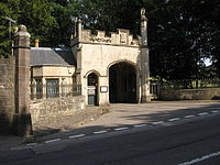 Photographie d'un portail de pierre situé en bordure de route.