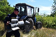 Member of the State Emergency Service of Ukraine carrying an unexploded Russian bomb in an agricultural field in southeastern Ukraine, 1 July 2022. The Russian invasion of Ukraine disrupted all parts of the grain agriculture and grain trade from Ukraine, further stressing a global supply chain that had already been seeing major price increases. Member of the State Emergency Service of Ukraine carrying an unexploded Russian bomb in an agricultural field in southeastern Ukraine.jpg