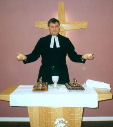 A minister, dressed in a cassock and preaching bands, presides over a service of Holy Communion