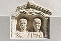 English: Upper part of a Roman grave stela showing the heads of a married couple, immured to the outside wall at the apsis` crest Deutsch: Oberteil einer römischen Grabstele mit der Reliefbüste eines Ehepaares, eingemauert am Scheitelpunkt der äußeren Apsiswand