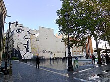 Das Chuuuttt !!! Fresko über die gesamte Höhe des Giebels eines alten vierstöckigen Gebäudes am Igor-Strawinsky-Platz.  Es zeigt in Schwarz auf weißem Hintergrund das Gesicht eines Mannes mit großen Augen, dessen Zeigefinger vor den Lippen erhoben ist.