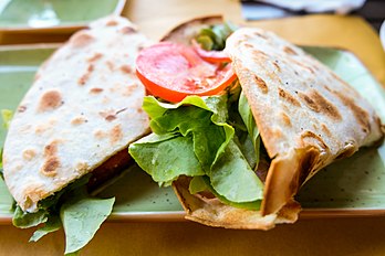 A traditional chickpea flour piadina served with salad and tomatoes, a common meal in northern Italy. Piadina Sandwich Breakfast with Salad and Tomatoes.jpg