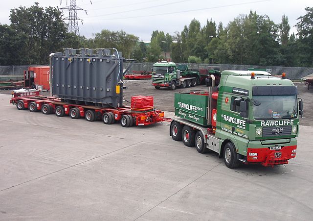 Large ballast tractor pulling a heavy load (a transformer) on a hydraulic modular trailer using a drawbar