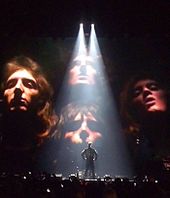 Williams on stage in Poland in 2015 performing Bohemian Rhapsody. He collaborated with Queen in recording We Are the Champions for the 2001 film A Knight's Tale
