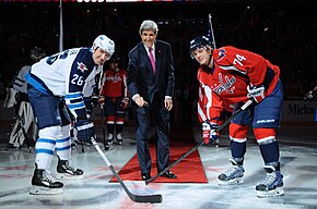 U.S. Secretary of State John Kerry prepares to drop the ceremonial first puck with Winnipeg Jets player Blake Wheeler and Washington Capitals player John Carlson. Secretary Kerry Prepares for Ceremonial Puck Drop With U.S. Olympians Wheeler, Carlson (12354110425).jpg