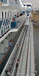 Rows of balconies are photographed along the left side of a cruise ship