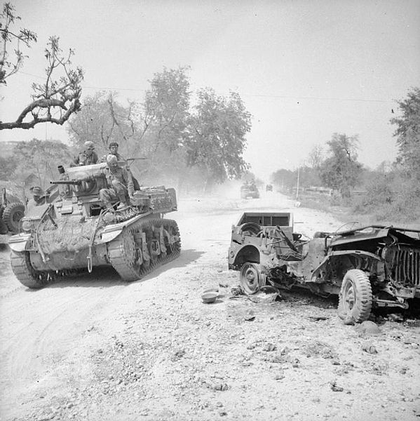 Stuart tank of 19th Indian Division passes a destroyed jeep on the outskirts of Mandalay shortly after the fall of Fort Dufferin, 19 March 1945.