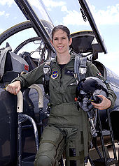 Eine Frau in Pilotenuniform vor dem offenen Cockpit eines Kampfflugzeugs