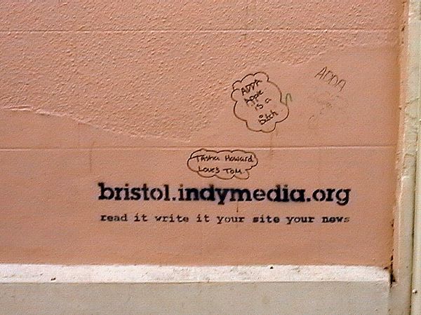 Graffiti in Bristol, United Kingdom, advertising the local chapter of Indymedia with the slogan "Read it, write it, your site, your news"