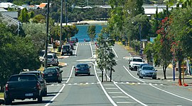 Boulevard with cars parked on each side, with river in background