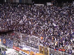 A firm is seen rooting for their team, Deportivo Saprissa, as the players enter the field.