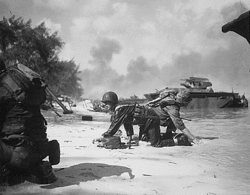 Two Marines crawl to their assigned positions on the beach on Saipan. Marines-at-saipan-194406.gif