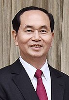 Trần Đại Quang is seen smiling while wearing a black suit, red tie and white shirt.