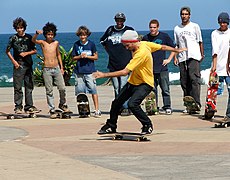 Un grupo de jóvenes se turnan para realizar maniobras de skateboarding y contemplar a los que las realizan.