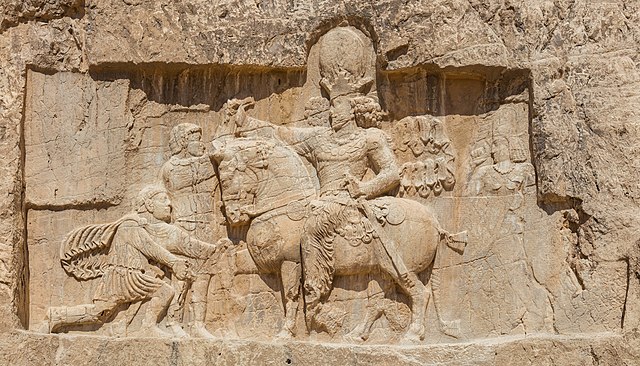 Rock-face relief at Naqsh-e Rostam of Persian emperor Shapur I (on horseback) capturing Roman emperor Valerian (standing) and Philip the Arab (kneelin