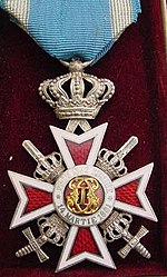 Type 2Knight's Cross. Version for military personnel with a crown above the cross, swords signifying a war time award. On incorrect, civilian pre-1932 ribbon. Orde van de Kroon van Roemenie met Zwaarden na 1932.jpg