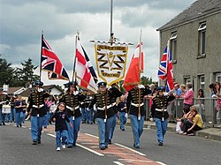The "Red Hand Defenders" flute band marching with the Orange Order in Newtownstewart on 12 July 2010. The flags being carried are the Union Flag, Ulster Banner and Boyntandard. Red Hand Defenders flute band parade in Newtownstewart - 12 July 2010 - geograph - 1963520.jpg