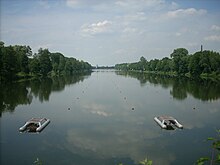 Zu sehen sind die Startvorichtigungen und die roten Bojenketten auf der von Bäumen gesäumten Regattastrecke.