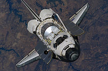 Discovery nadert het internationale ruimtestation ISS tijdens STS-121.  De lading in het vrachtcompartiment van de shuttle zou later in de missie aan het ISS worden vastgemaakt.  De unieke 'traan'-functie van het ruimteschip, bestaande uit verschillende zwarte tegels nabij de cockpit, is duidelijk zichtbaar.