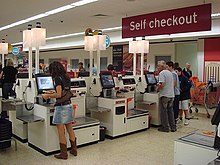 NCR Corporation model of self-service checkouts and fast-lane at a Sainsbury's store. Self checkout using NCR Fastlane machines.jpg