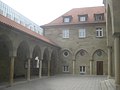 Arkadenhof (Paradies) der katholischen St. Fideliskirche in Stuttgart. Links: Arkadengang, mitte: Pfarrhaus mit Blendarkaden, rechts: Hauptportal der Westfassade.