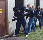 En enhet från den amerikanska militärpolisen USACIDC använder en murbräcka för att öppna en dörr