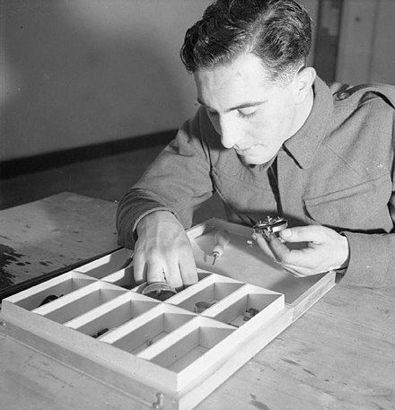 British soldiers took standardized tests during the Second World War.  This new recruit is sorting mechanical parts to test his understanding of machinery.  His uniform shows no name, rank, or other sign that might bias the scoring of his work.