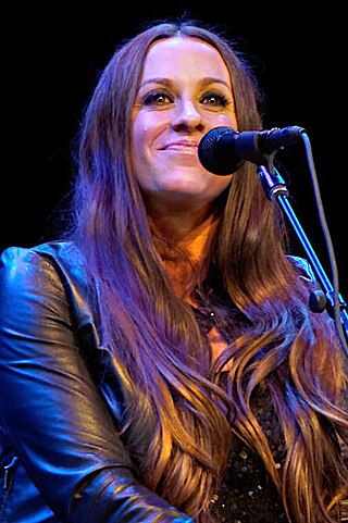 A woman wearing a black leather jacket smiling behind a microphone