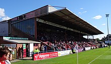 L'un des stands du terrain de football de l'association Bootham Crescent, avec des supporters assis et une pelouse en dessous