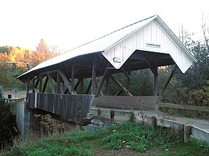 Dřevěný krytý most s otevřenými stranami a nosníky ve tvaru X.