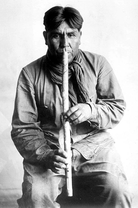 Cipriano Garcia playing a flute of the Tohono O'odham culture. Photograph by Frances Densmore taken in 1919.