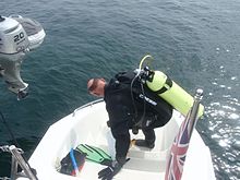 Preparing to dive from a small stern platform on a sailing catamaran. Diver preparing to dive on RLS survey PA262752.JPG