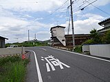 カーブミラーの右が一里塚跡の石碑。 中央の建物の右手前の電柱が、左方向にある川辺橋方面から「くの字」なりに曲がった先にある最初の電柱。