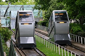 Foto naar beneden kijkend langs de uitbijter (Frans: butte) van Montmartre met de achterkant en het dak van een hut.  Een panorama van Parijs hieronder vult de achtergrond.