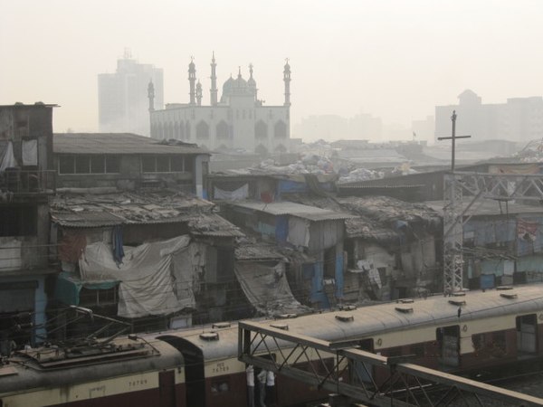 Shanty dwellings next to railway tracks in Dharavi (about 2010). A mosque inside the slum is visible. The railway network provides mass transit to the