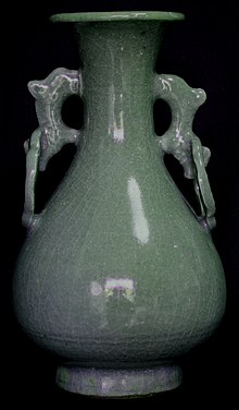 Vysoký, štíhlá, modro-zelená váza se dvěma uchy, každé s dvěma otvory, malým horním a větším spodním.