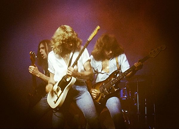 The "Frantic Four" lineup; left-to-right: Francis Rossi, Rick Parfitt and Alan Lancaster (obscured: John Coghlan) performing at the Hammersmith Odeon 