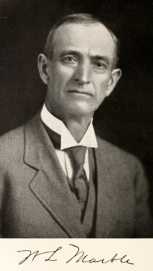 Black and white photograph of a man in a suit facing right