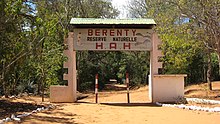 Uma estrada de terra passa por baixo de uma placa em arco decorada que demarca a Reserva Privada Berenty.