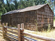 Bölünmüş bir raylı çitin yanında kiremitli bir kütük kabin, Big Sur sahilindeki en eski yapıdır.