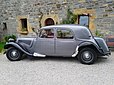 Une Citroën Traction 11 BL (Berline Légère) des années 1950, dans une belle et rutilante livrée grise métallisée avec les ailes noires.